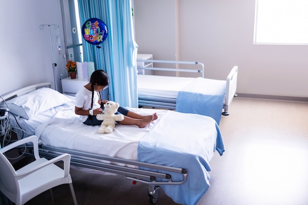 Patient sitzt mit Teddybär auf dem Bett