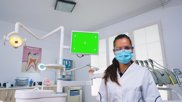 Patienten-Pov des Zahnarztes, der Zahnprobleme und Diagnose für Zahninfektionen mit Monitoreinheit mit grünem Bildschirm erklärt. Stomatologie-Spezialist, der auf Mockup, Kopienraum, Chroma-Display zeigt