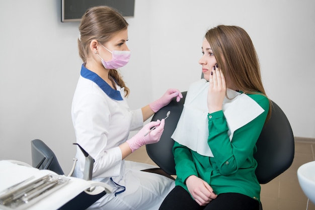 Patientin beim Zahnarzt klagt über Zahnschmerzen in der Zahnarztpraxis