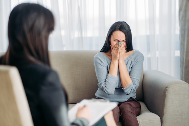 Patientin sitzt auf Sofa bei Psychotherapeutin