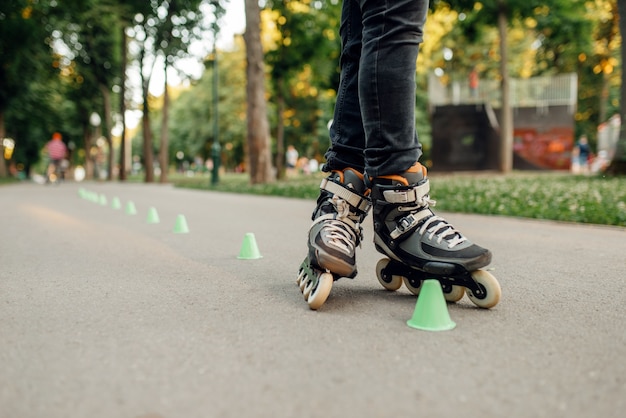 Patinação, patinador masculino rolando em torno dos cones no parque. Patinação urbana, esportes radicais ativos ao ar livre, lazer juvenil, patinação