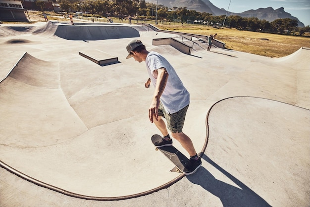 Patinador deportivo y hombre en el parque de patinaje en la ciudad realizando trucos de acción o acrobacias Patineta de fitness y patinador masculino joven en práctica de entrenamiento en rampa o entrenamiento al aire libre en la ciudad para hacer ejercicio