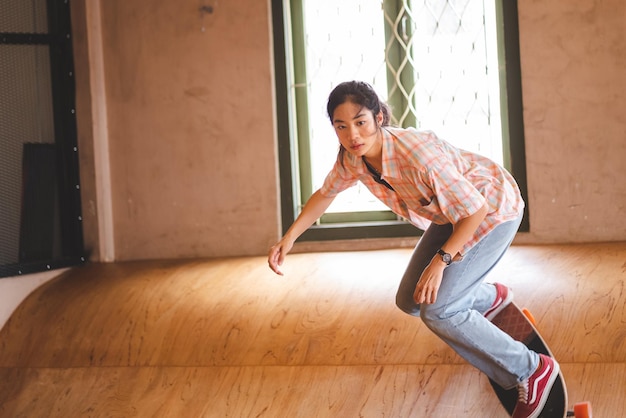 Patinadora asiática haciendo trucos saltando en el garaje subterráneo Actividad urbana estilo de vida interior