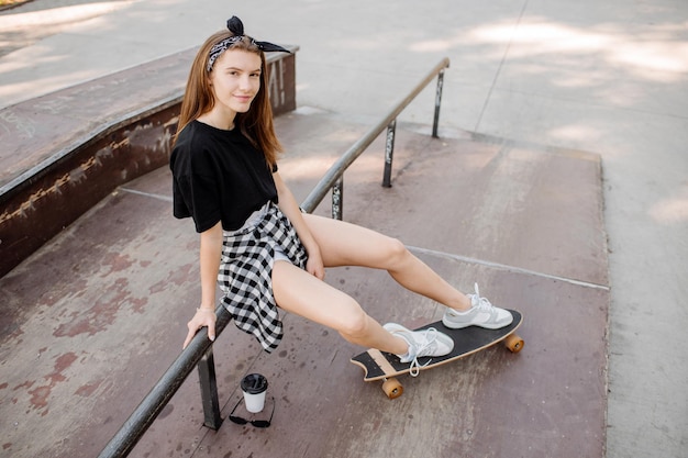 Patinadora feminina com um skate relaxando na pista de patinação