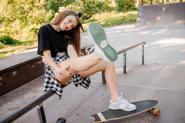 Patinadora feminina com um skate relaxando na pista de patinação