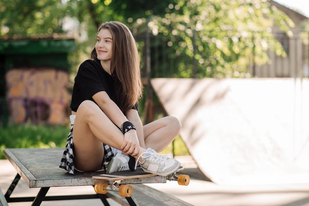 Una patinadora con patineta está sentada y descansando en el parque de patinadores