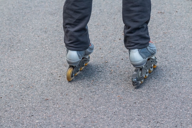 patinaje sobre ruedas en la calle de la ciudad, primer plano de las piernas. piernas de adolescentes montando patinaje sobre la calle. Rodillos grises en las piernas piernas de hombres deportistas en un patín de ruedas a pie closeup