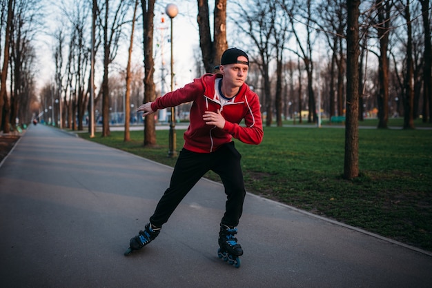 Patinaje sobre ruedas paseos por la acera en el parque de la ciudad. Ocio de rollerskater masculino
