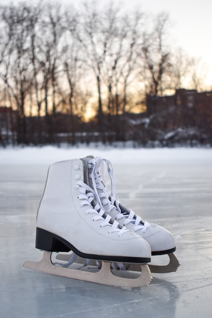 Los patines de las mujeres blancas se paran en el hielo. Vista superior. Pista de hielo de entretenimiento de invierno.