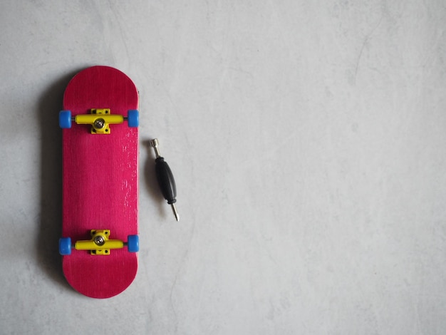 Foto patineta de dedos de madera de color rosa con camiones amarillos y ruedas azules aisladas sobre un fondo blanco