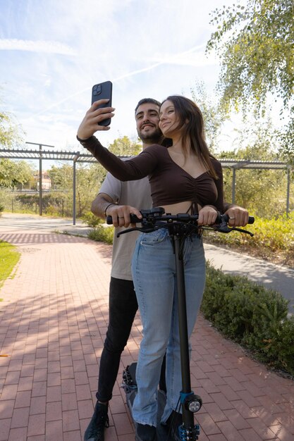 Patinete eléctrico Un par de enamorados se toman una selfie montados en un patinete eléctrico y sonríen para la foto