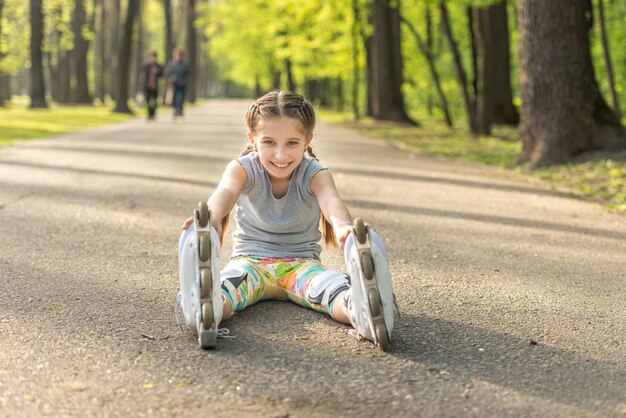 Patins de menina sentada no asfalto, esticando