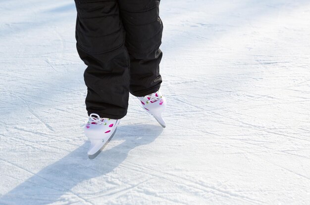 Patins deslizantes de plástico infantil com close-up de ajuste de tamanho no gelo no inverno ao ar livre. rolando e deslizando em dia de sol gelado, esportes de inverno ativos e estilo de vida