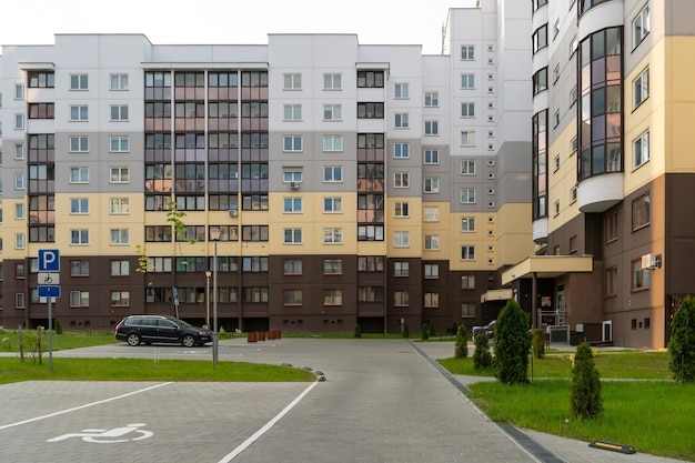 El patio de un gran complejo residencial de varias plantas en verano con plazas de aparcamiento para coches Plazas de aparcamiento para conductores con discapacidad