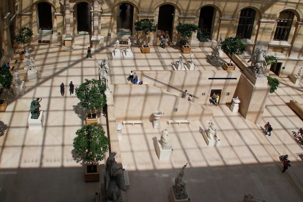 Foto pátio interno do museu do louvre com tons duros da pirâmide de vidro