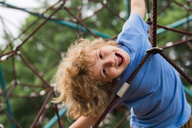 El patio de recreo al aire libre para niños en el parque de verano niño juega en el patio bajo el retrato del árbol de