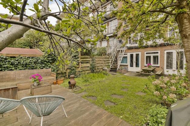 Un patio trasero con una casa y una terraza de madera.