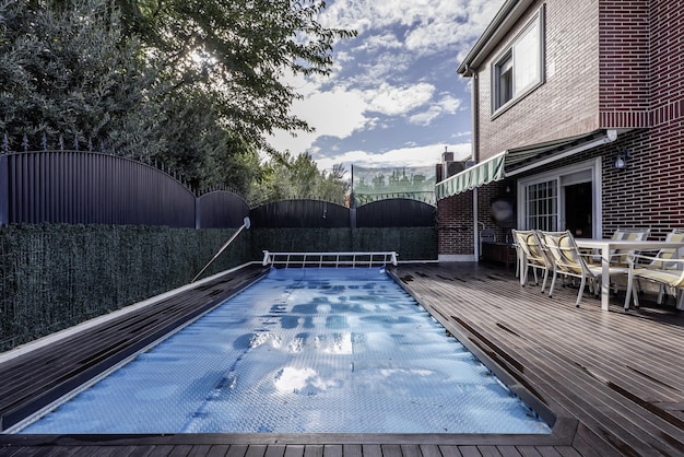 Foto el patio trasero de una casa unifamiliar con una piscina cubierta por un lienzo protector retráctil