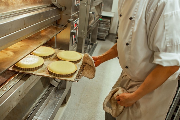 Patissier puso pasteles para hornear en el horno en una cocina de panadería europea tradicional con ba