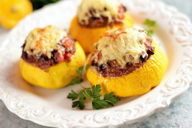 Patissons amarelos orgânicos recheados com carne, cebola, cenoura, cogumelos e pimenta vermelha assados no forno com queijo.