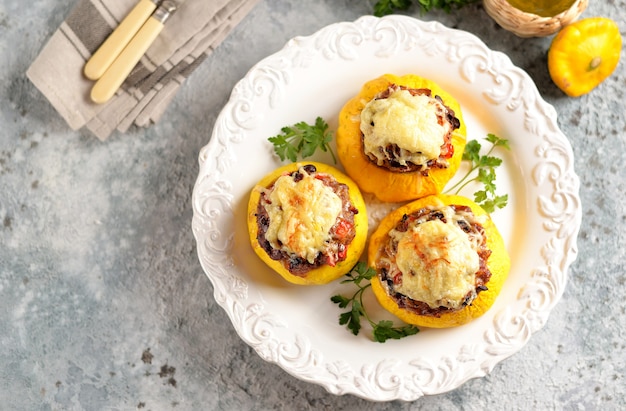 Patissons amarelos orgânicos recheados com carne, cebola, cenoura, cogumelos e pimenta vermelha assados no forno com queijo.