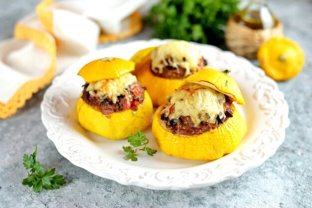 Patissons amarelos orgânicos recheados com carne, cebola, cenoura, cogumelos e pimenta vermelha assados no forno com queijo.