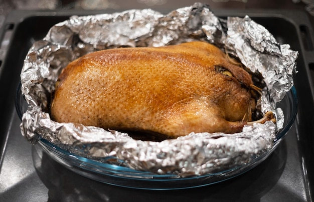 Pato com maçãs assadas em papel alumínio em uma bandeja