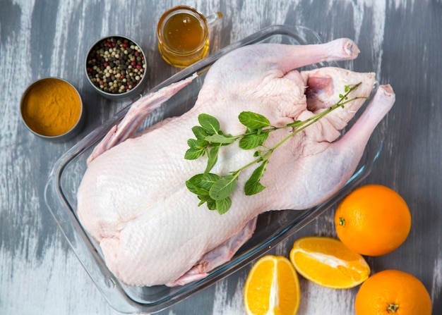 Foto pato crudo con especias listas para hornear sobre fondo de madera