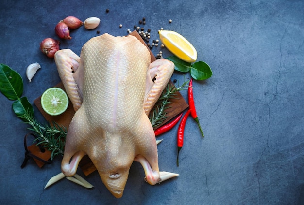 Pato crudo con especias listo para cocinar sobre fondo negro carne de pato fresca en un plato para comida pato entero y limón romero chile ajo vista superior