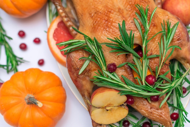 Pato de Natal ou Ação de Graças assado para jantar festivo tradicional com maçãs alecrim toranjas na toalha de mesa branca decorada com abóboras e velas Foco seletivo