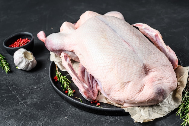 Pato entero crudo, pimienta rosa y romero.