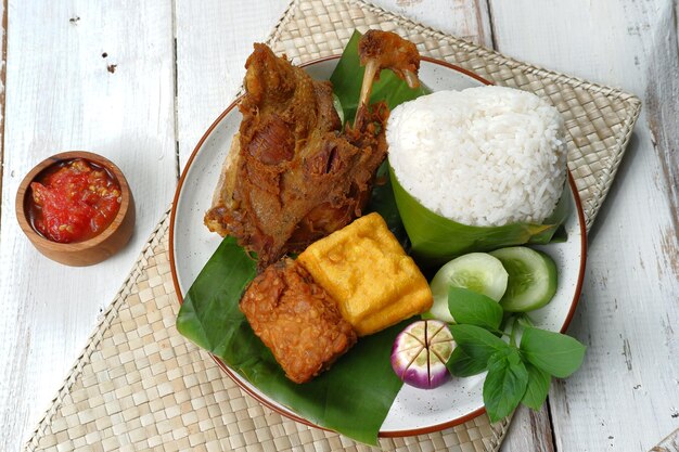 Pato frito servido con arroz, verduras y sambal (nasi bebek), estilo de comida indonesia.