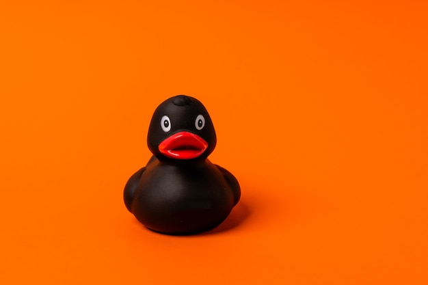 Pato de goma negro sobre un fondo naranja