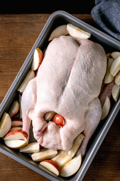Pato inteiro cru cru na bandeja com maçãs