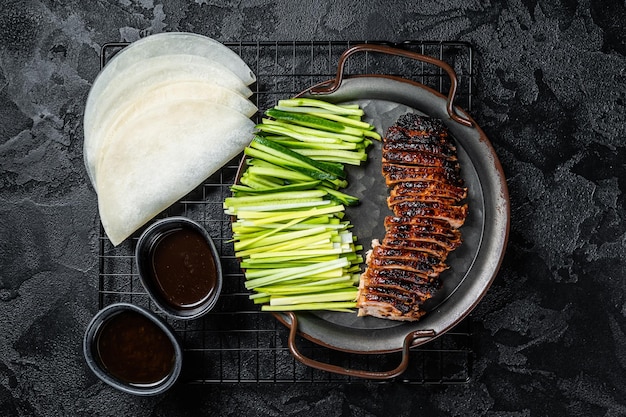 Pato Pekín servido con cebollas verdes de pepino y panqueques chinos de trigo asado con salsa Hoysin Fondo negro Vista superior