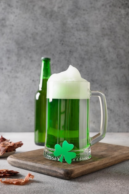 Patrick's Day grünes Bier mit Kleeblatt und ruckartigem Fleisch auf grauem Hintergrund Hochformat Nahaufnahme