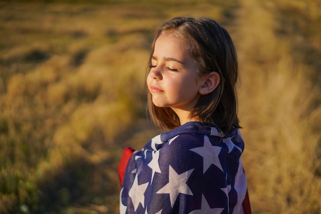 Patriota de garotinha feliz correndo no campo com bandeira americana