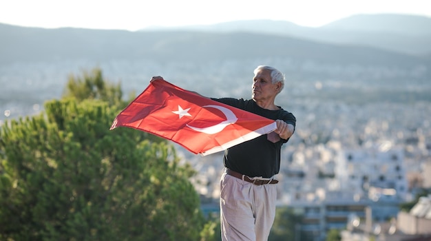 Patriotischer älterer Mann feiert den türkischen Unabhängigkeitstag mit einer Nationalflagge in seinen Händen, den Tag der Verfassung und der Staatsbürgerschaft