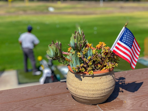 Patriotischer Blumentopf mit amerikanischen Flaggen und Golfer im Hintergrund Dekoration der amerikanischen Flagge