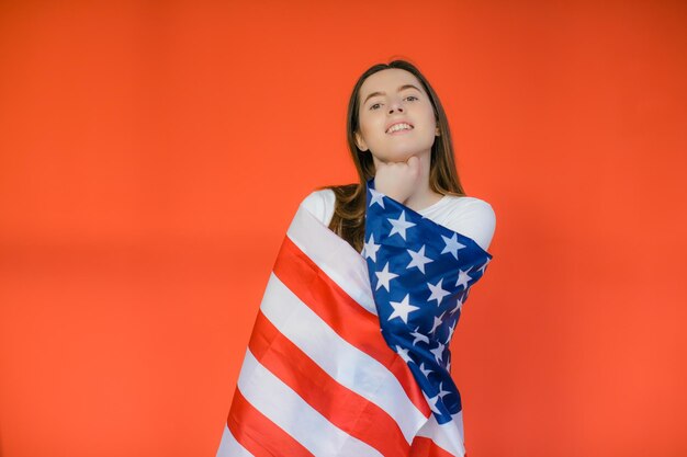 Patriotischer Feiertag Fröhliche junge Frau mit amerikanischer Flagge auf rotem Hintergrund USA feiern den 4. Juli