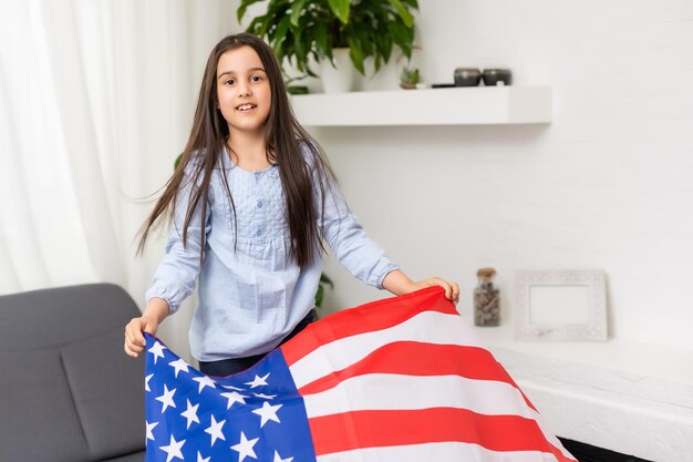 Patriotischer Feiertag. Glückliches Kind, süßes kleines Mädchen mit amerikanischer Flagge. Die USA feiern den 4. Juli.