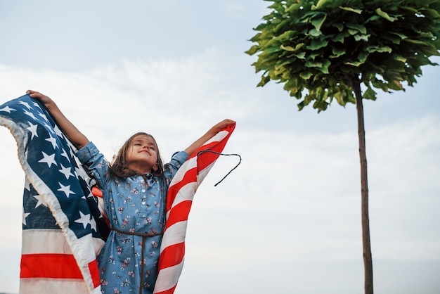 Patriotisches weibliches Kind mit amerikanischer Flagge in den Händen