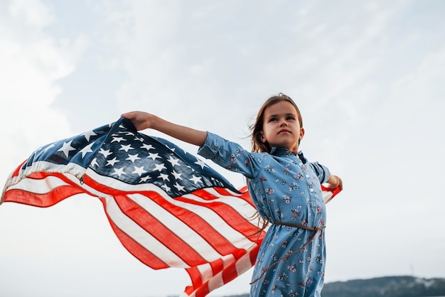 Patriotisches weibliches Kind mit amerikanischer Flagge in den Händen