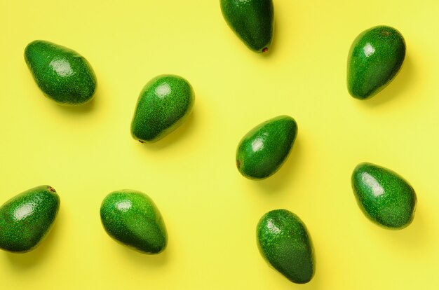 Patrón de aguacate sobre fondo amarillo. Vista superior. Bandera. Diseño de arte pop, concepto creativo de comida de verano. Aguacates verdes, estilo minimalista.