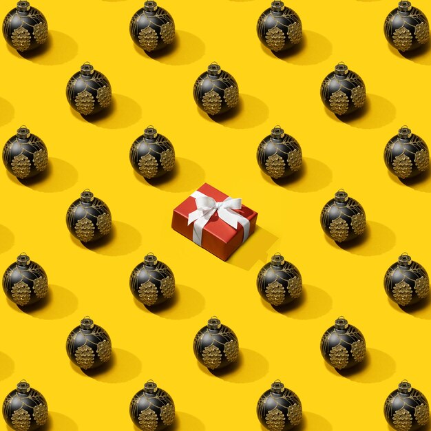 Foto patrón de año nuevo de la decoración de la bola de navidad negra con caja de regalo en amarillo