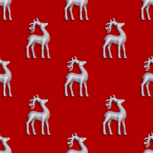 Patrón de Año Nuevo y Navidad sin costuras con ciervos plateados sobre un fondo rojo