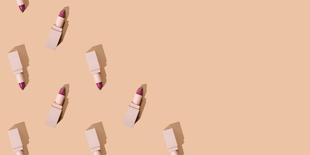 Patrón con barras de labios en un banner web de cosméticos de fondo beige con espacio de copia para texto