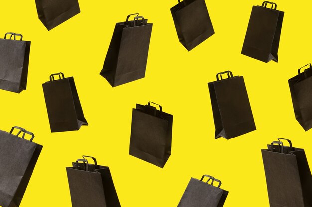 Foto patrón de bolsas de la compra de venta negras están volando sobre fondo amarillo. concepto de idea creativa de viernes negro