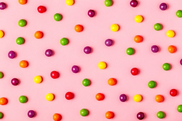 Patrón de caramelos de colores sobre un fondo rosa