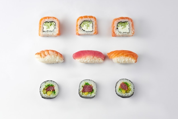 Patrón de diferentes tipos de rollos de sushi con atún y salmón sobre un fondo blanco.